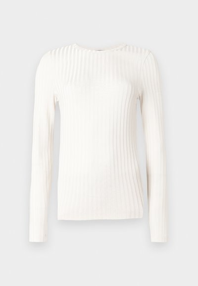 Top blanc à manches longues en tissu côtelé. Il présente un col rond et une silhouette ajustée, avec des rayures texturées courant verticalement.