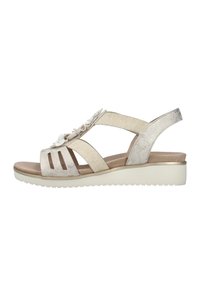 Beige sandal med en texturerad yta, med blommig accent, korskorsande remmar och en vit, kraftig sula för ökad höjd och komfort.