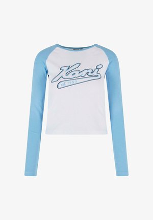 Pika pikkade varrukatega särk, millel on valge keha ja helesinised ribaga varrukad, ees sinise kiri "Kani asut. 1989".