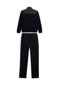 Chándal deportivo negro que incluye una chaqueta con cremallera y cuello alto, y pantalones a juego. La tela es lisa y tiene un corte holgado.