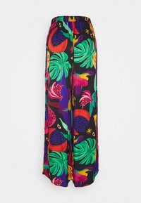 Pantalons à jambes larges avec un imprimé tropical coloré comportant des feuilles vertes, des fleurs rouges et roses, et des formes abstraites multicolores sur un fond noir.