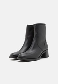 Black leather ankle boots with a rounded toe, mid-height block heel, and minimal stitching detail, featuring a smooth texture.
