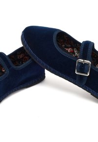 Granatowe aksamitne buty Mary Jane z srebrną klamrą, szytymi brzegami i wzorem paisley wewnątrz na białym tle.