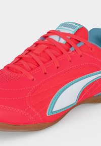 Φωτεινό κόκκινο αθλητικό Puma με τόνους τιρκουάζ και λευκού, κόκκινα κορδόνια και σόλα από καουτσούκ, σε κοντινή πλάγια όψη.