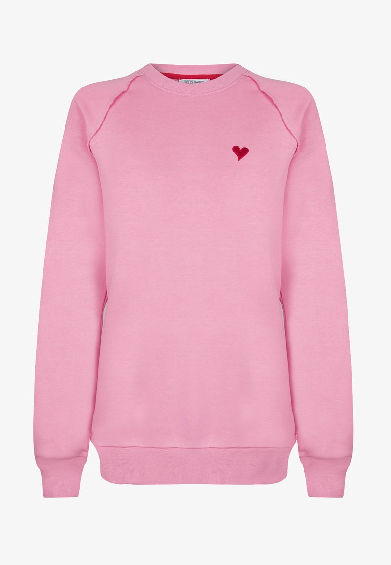 Felpa rosa con scollatura a girocollo, maniche raglan, polsini e orlo a costine, caratterizzata da un piccolo ricamo a forma di cuore rosso sul lato sinistro del petto.