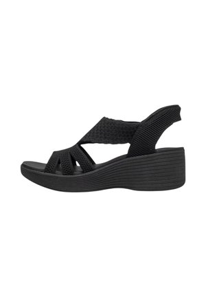 Sort kile-sandal med vævede stofremme og åben tå, med slingback-hæl og tekstureret sål.