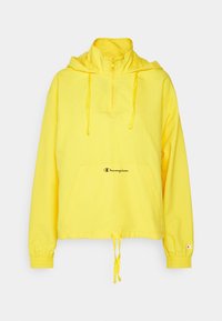 Gul pulloverjacka med en framficka, halvdragkedja, justerbar huva och elastiska ärmslut, med en liten logotyp framtill.