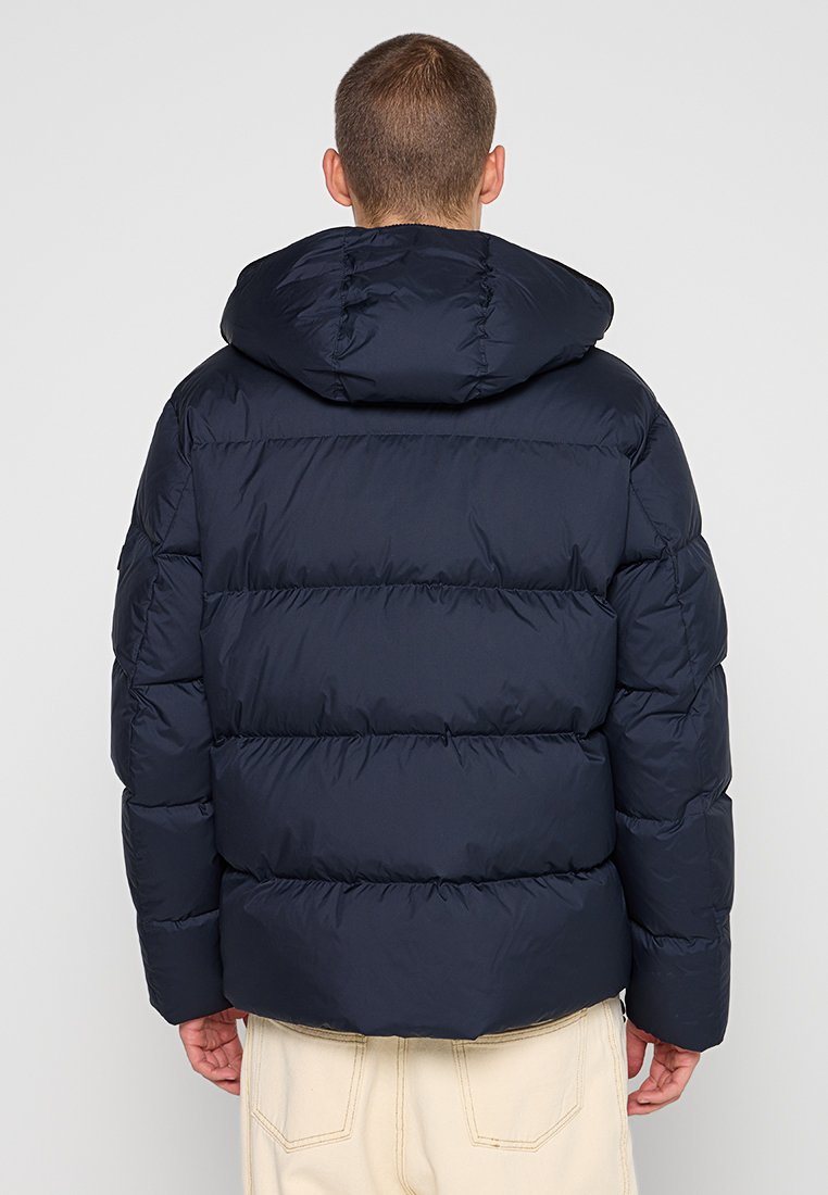 Marineblauer Steppjacke mit Kapuze, die horizontale gesteppten Abschnitte und eine glatte, glänzende Oberfläche aufweist. Die Rückansicht zeigt ein kurzes Design.