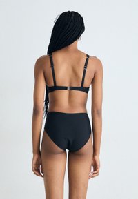 Juodas bikini komplektas, kuris apima braletę su reguliuojamomis petnešėlėmis ir aukštu liemeniu, pagamintas iš lygaus, elastingo audinio.