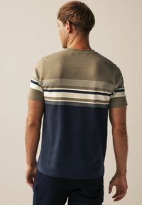 Tricou cu mânecă scurtă, cu dungi orizontale în culorile măsliniu, bej și bleumarin. Material moale, cu croială lejeră și gât rotund.
