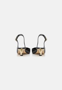 Sorte læder slingback-sko med en guldfarvet accentdetalje og et unikt hældesign. Glat tekstur og minimalistische silhuet.
