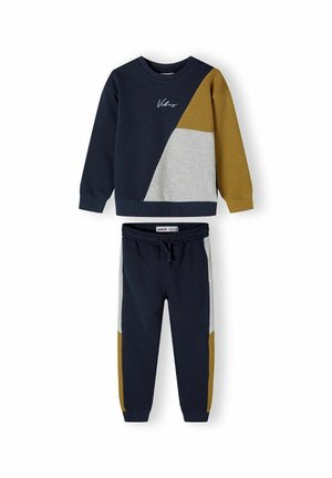 Marineblaues Sweatshirt mit grauen und senfgelben Akzenten, das ein geometrisches Design und gestickten Text zeigt. Passende marineblaue Jogginghose mit farblich abgesetzten Seiten.