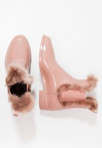 Botas de lluvia de tobillo en un brillante color rosa claro, con suave ribete de piel sintética marrón alrededor de la abertura y paneles laterales elásticos.