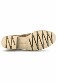 Suela de zapato Gabor, de goma beige con patrón texturizado, presenta surcos profundos para mayor tracción y el logo de Gabor estampado cerca del talón.