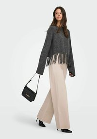 Pelēks saīsināts džemperis ar frizūru apakšmalā, apvienots ar plašām pelēkām biksēm. Modelis tur mazu melnu rokassomu un valkā melnas augstpapēžu kurpes.