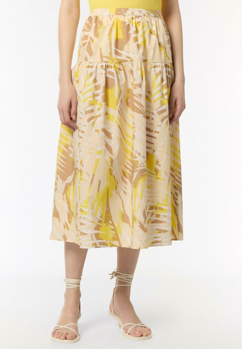 Midi spódnica w kwiatowy wzór w kolorze żółtym, beżowym i białym. Wykonana z lekkiego materiału, z marszczonym stanem i warstwowym fasonem. Modelka boso.