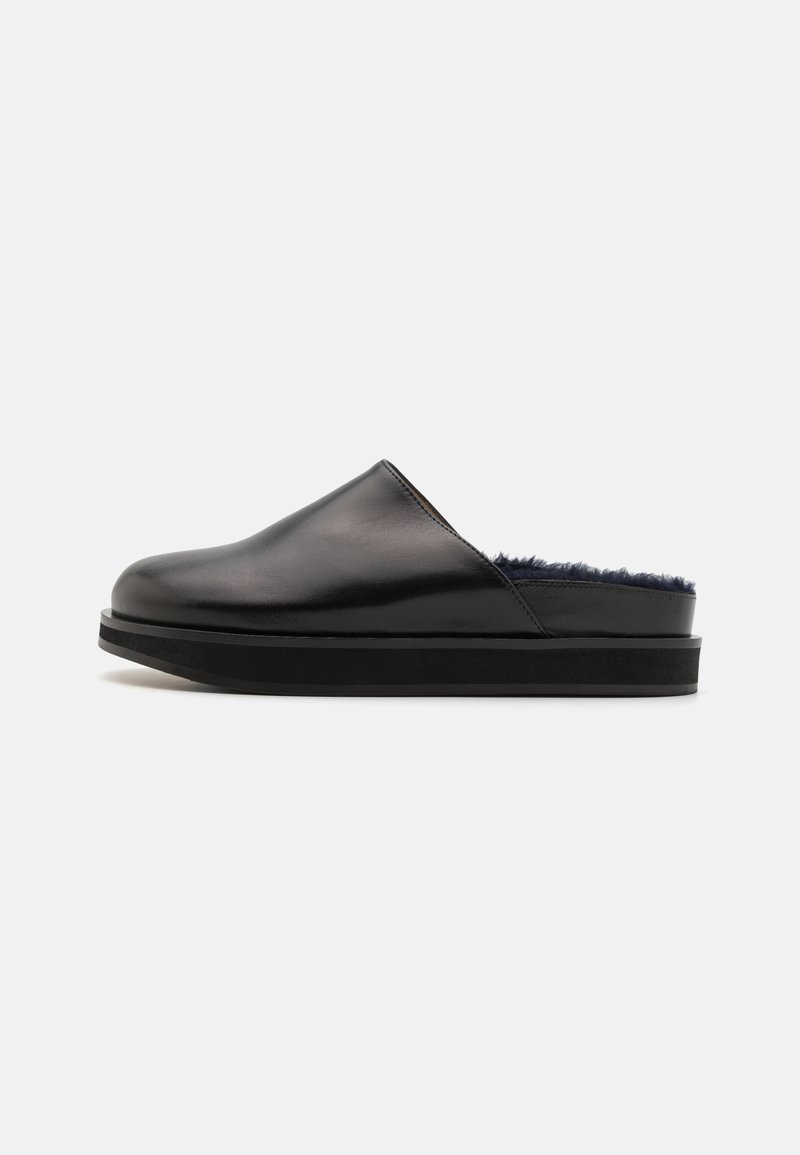 Fekete bőr slip-on cipők puha belső béléssel és lapos, texturált gumitalppal. Simára kidolgozott felületük és minimalista dizájnjuk jellemzi �őket.