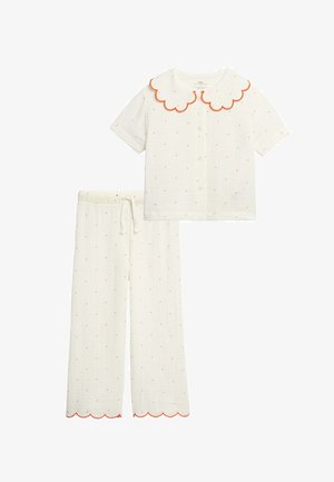 Wit tweedelig pyjamaset met een kortemouwen knoopjes top en een broek met elastische taille, met kleine rode stippen en oranje gegolfde randen.