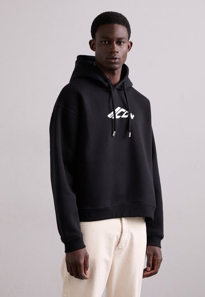 Hoodie noir en matériau doux, avec une poche kangourou à l'avant, un capuchon à cordon et un logo blanc sur la poitrine.
