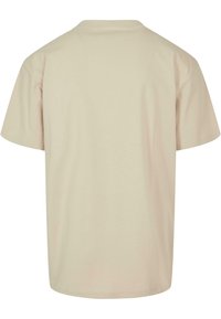 Beige t-skjorte, korte ermer, rund hals, myk bomullstoff, avslappet passform, subtil struktur, ingen mønstre eller grafikk. Vist fra baksiden.