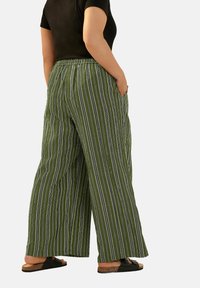 Vidaintyggbyxor i mörkgrön med vita vertikala ränder. Elastisk midja, sidofickor och textil med struktur. Svarta sandaler med korksål.