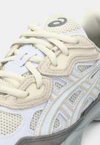 Λευκό και μπεζ αθλητικό παπούτσι με υλικό από δίχτυ και σουέντ, με υφή στο σώμα, ανοιχτές αποχρώσεις και επίπεδους, στρογγυλούς κορδόνια.