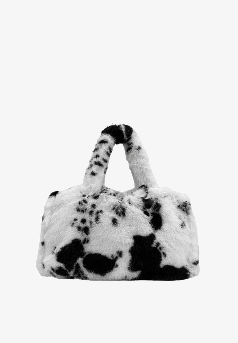 Sac à main en fausse fourrure à imprimé vache noir et blanc, avec une forme arrondie et deux petites poignées, présentant une texture douce et des taches prononcées.