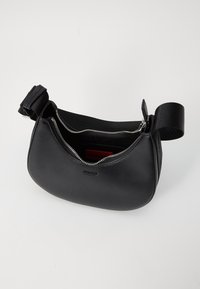 Borsa a spalla in pelle nera con forma curva, caratterizzata da una cerniera argentata e logo sul davanti. Interno foderato in stoffa rossa.