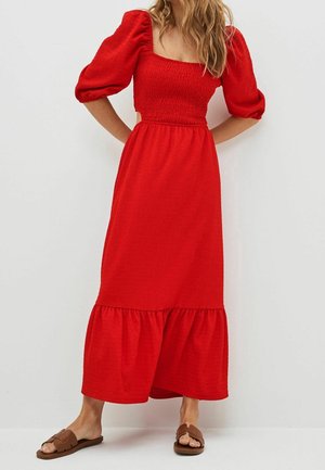 Robe maxi rouge avec encolure carrée, manches bouffantes et corsage smocké. Ourlet à volants et tissu texturé. Assortie à des sandales plates marron.