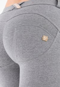 Leggings grises con textura suave, que cuentan con un bolsillo lateral y un detalle de herrajes en tono dorado. Confeccionados con tejido elástico para mayor comodidad.