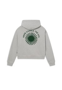 Grijze cropped hoodie van zacht materiaal, met een groene zonafbeelding en de tekst "HIER KOMT DE ZON" gedrukt op de achterkant.