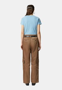 Pantaloni cargo marroni con due tasche laterali, abbinati a una maglietta azzurro chiaro. L'outfit presenta una cintura nera e un design comfort.