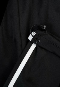 Czarna tkanina o teksturowanej powierzchni z białym akcentem wzdłuż i regulowanym zapięciem na sznurek.