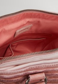 Wnętrze różowej torebki wyłożone gładką tkaniną. Zawiera kieszeń na zamek i przegródki na karty, z delikatnym teksturowanym wzorem na zewnętrznej warstwie.