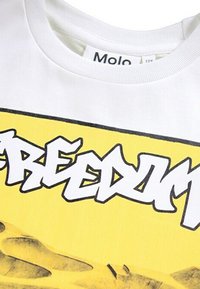 Hvid bomulds T-shirt med en stor gul grafik med ordet "FREEDOM" i stiliseret sort skrift, rund halsudskæring og korte ærmer.