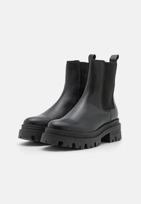 Bottines en cuir noir avec des panneaux latéraux en élastique, semelle en caoutchouc épaisse, bout arrondi et languettes à l'arrière pour un enfilage facile.