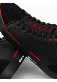 Černé tenisky s kombinací hladké kůže a semiše, červenými akcenty na tkaničkách a logem na boku, s elegantním designem.