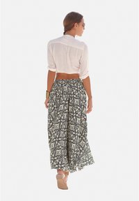 Witte cropped blouse en lange zwart-witte-gepatroniseerde rok. Rok heeft ingewikkelde scroll- en bloemontwerpen, met een vloeiende textuur en enkel lengte.