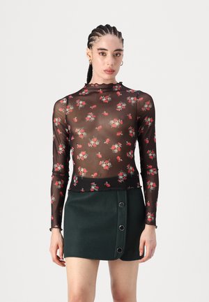 Sheer black long-sleeve top with red floral pattern, scalloped neckline, paired with a dark green mini skirt featuring side buttons.