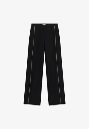 Zwarte wijde broekspijpen met beige strepen aan de zijkant en een elastische tailleband met wit "GUESS" logo.