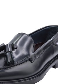 Black leather loafer with tassel detail, smooth finish, round toe, and contrasting leather lining, featuring detailed stitching and a rubber sole.