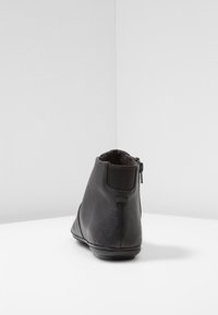Black leather ankle boot with back zipper and elastic panel, set against a plain white background.
