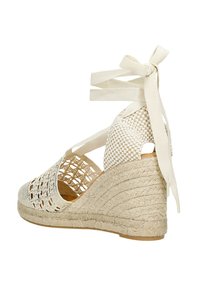 Wedge sandaal met een geweven beige bovenkant, vetersluiting met linttouwtjes, en een gestructureerde, gevlochten jute wedge hak.