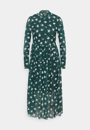 Mörkgrön långärmad midikjol med vitt blommönster, hög halsringning, figursydd midja och halvgenomskinlig kjolöverdrag.