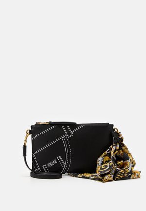 Czarna prostokątna torba na ramię z białymi przeszyciami, złotymi elementami metalowymi oraz ozdobną czarno-złoto-białą apaszką zawiązaną z jednej strony.