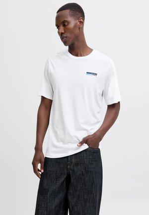 White cotton t-shirt with short sleeves, featuring a small blue and black logo on the front, paired with dark denim jeans.