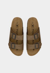 Sandali marroni con due cinturini regolabili, fibbie in metallo scuro e una soletta morbida. Logo impresso sulla soletta. Suola piatta, design semplice.