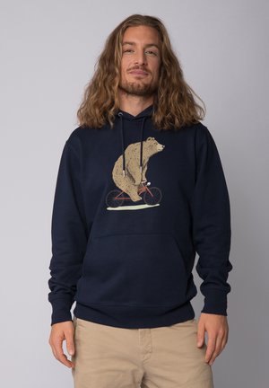 Marineblauwe hoodie van zachte stof met een ontwerp van een beer die op een fiets rijdt in beige en bruin, met een voorste kangoeroezak en een capuchon met trekkoord.