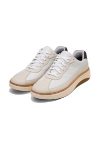 Lätta sneakers i vit läder med beige accenter, med en tjock krämfärgad sula, rund tå och vita snören. Svart häl detalj.