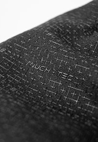 Black textured fabric featuring a grid pattern and embossed "TOUCH.TEC" text, indicating a specialized material for touch sensitivity.